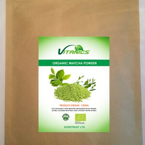 May include: A brown paper bag with a white label that says "VITANICS ORGANIC MATCHA POWDER". The label also includes a picture of green matcha powder and leaves, and the text "PRODUCT ORIGIN: CHINA". The label also includes two green organic certifications.