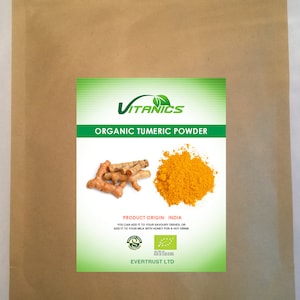 May include: A brown paper bag with a label that reads "VITANICS ORGANIC TUMERIC POWDER". The label also features an image of turmeric root and turmeric powder. The label states "PRODUCT ORIGIN: INDIA" and "YOU CAN ADD IT TO YOUR SAVOURY DISHES, OR ADD IT TO YOUR MILK WITH HONEY FOR A HOT DRINK". The label also includes a green organic certification logo and says "EVERTRUST LTD".