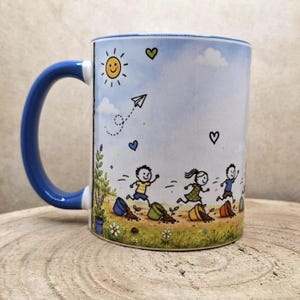 May include: White ceramic mug with a blue handle and rim. The mug features a whimsical illustration of children running through a field with a smiling sun, paper airplane, and hearts. The design includes flowers and potted plants.