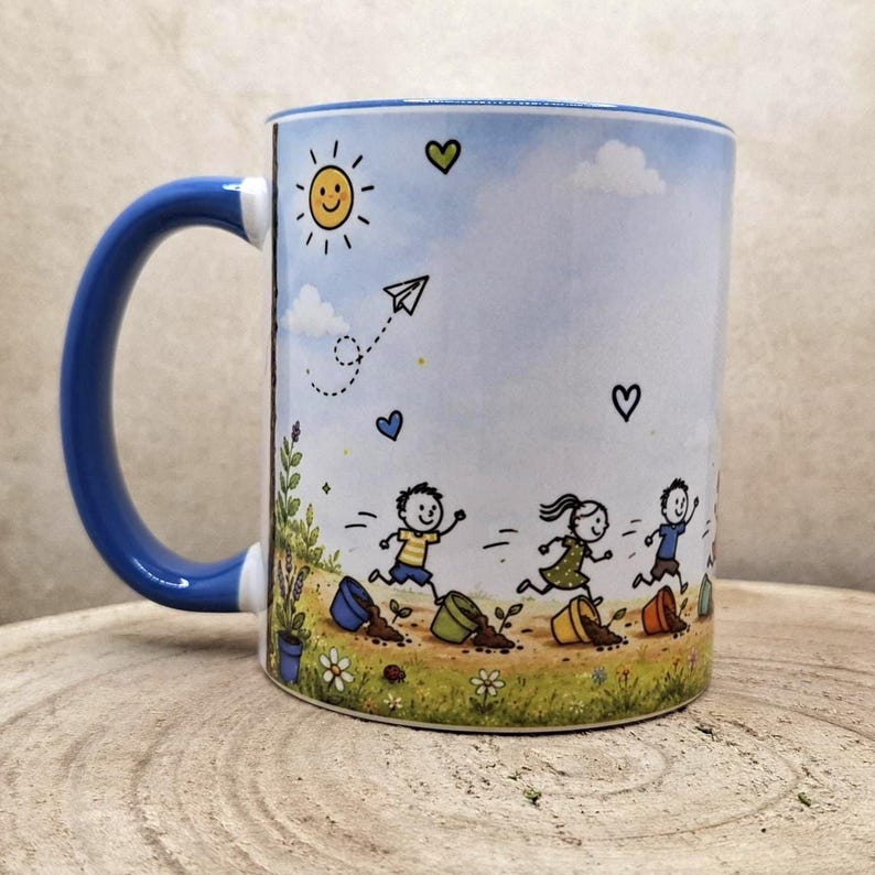 May include: White ceramic mug with a blue handle and rim. The mug features a whimsical illustration of children running through a field with a smiling sun, paper airplane, and hearts. The design includes flowers and potted plants.