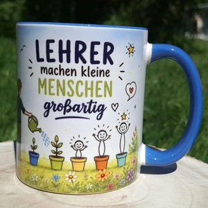 May include: White ceramic mug with a blue handle and rim. The mug features the German text "LEHRER machen kleine MENSCHEN gro&szlig;artig" with illustrations of plants and children. A person is watering the plants. Flowers are at the bottom.