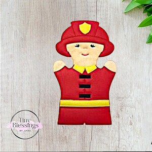 Puede incluir: Marioneta de mano de fieltro rojo de un bombero que lleva un casco amarillo con un uniforme rojo y amarillo. La marioneta tiene una cara sonriente con ojos negros y una boca negra.