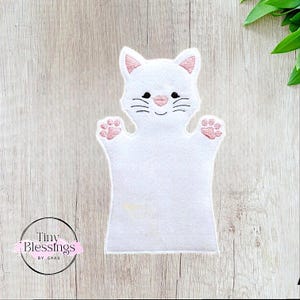 May include: White felt hand puppet shaped like a cat with pink embroidered paws and facial features. The puppet has a smiling expression.