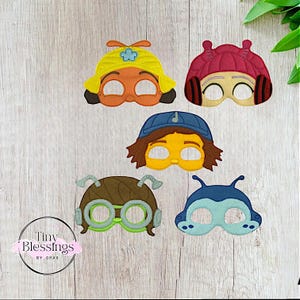 Op de afbeelding: Vijf viltmaskers voor kinderen met personages uit de kindershow 'The Backyardigans'. De maskers zijn geel, roze, blauw, bruin en groen. De maskers hebben vilt ogen en monden.