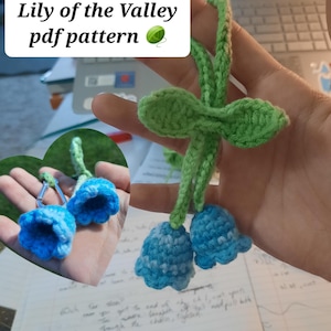 Puede incluir: Llavero de ganchillo con una flor de lirio de los valles. El llavero está hecho con hilo azul y verde. La imagen incluye el texto "Crochet Keychain Lily of the Valley pdf pattern".