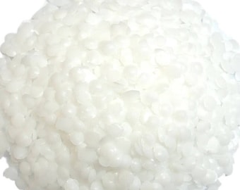 May include: A large, rounded pile of small, solid, white wax pellets. Each individual pellet is circular, smooth, and opaque, clustered together to form a dense, textured mound that is uniform in color and shape throughout the entire collection.