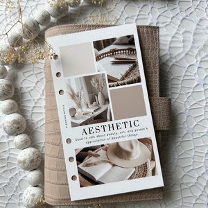 Pode incluir: Um cart&atilde;o branco com o texto "AESTHETIC" e a defini&ccedil;&atilde;o "Usado para falar sobre beleza, arte e a aprecia&ccedil;&atilde;o das coisas bonitas pelas pessoas." O cart&atilde;o &eacute; decorado com quatro imagens de um vaso branco com flores secas, um caderno e l&aacute;pis em uma bandeja tecida, um livro com um chap&eacute;u em cima e uma amostra de cor branca e bege.