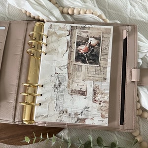May include: A blush pink leather planner with gold rings and a white page with a vintage floral design and the text "Planning with..."