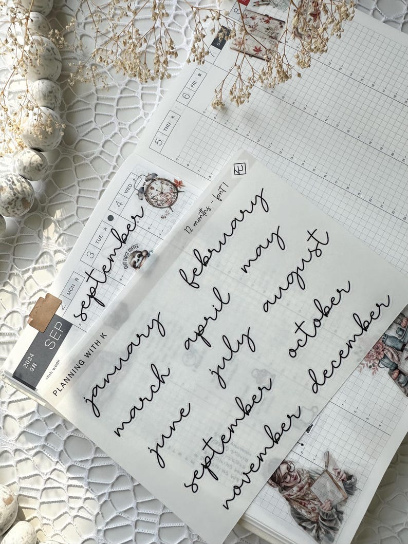 May include: A sheet of clear stickers with handwritten month names in black ink. The stickers are for use in a planner or journal.