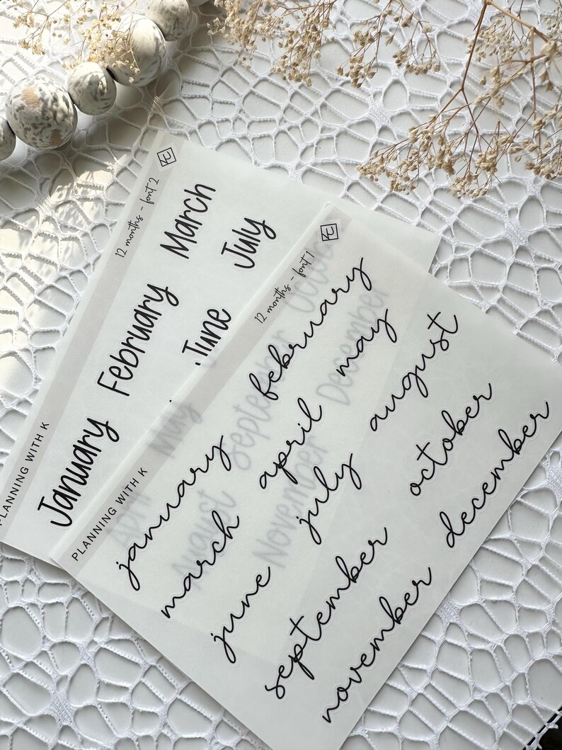 May include: A set of twelve clear stickers with handwritten month names in black ink. The stickers are designed for use in planners and journals.