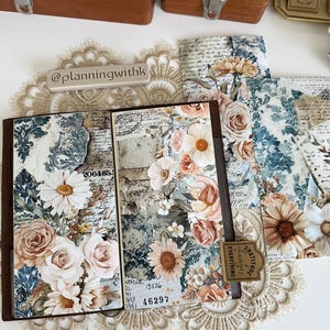 May include: A brown leather bound journal with floral patterned paper on the cover. The journal is open to reveal a page with handwritten notes and a sticker that says "Gratitude Changes Everything".