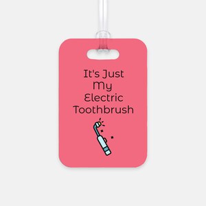 May include: Pink luggage tag with a white outline and a black handle. The tag has a black and white illustration of an electric toothbrush with the text "It's Just My Electric Toothbrush".