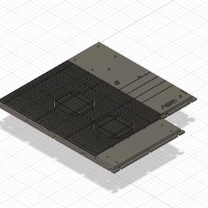 Puede incluir: Una placa de metal gris con dos recortes circulares y una superficie texturizada. La placa está unida a una placa de metal gris más pequeña con una serie de recortes rectangulares.