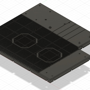 Op de afbeelding: Een zwarte metalen plaat met twee achthoekige uitsparingen en een rasterpatroon. De plaat heeft een verhoogd gedeelte met een reeks rechthoekige sleuven.