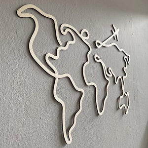Peut inclure: Une carte du monde en bois blanc avec une petite découpe d'avion au-dessus de l'Amérique du Nord.