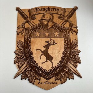 May include: A wooden wall plaque featuring a laser-engraved coat of arms with a central shield displaying a stag, three stars, and a knight's helmet. Two crossed swords are positioned behind the shield, framed by oak leaves with the text Daugherty and Ar nDúchas.