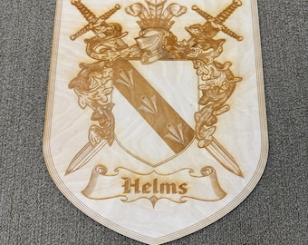 Könnte beinhalten: Holzfamilienwappen mit dem Namen "Helms" auf einem Banner graviert. Das Wappen zeigt einen Schild mit diagonalem Design, einen Helm, Schwerter und dekorative Elemente. Das Holz hat eine helle, natürliche Oberfläche.
