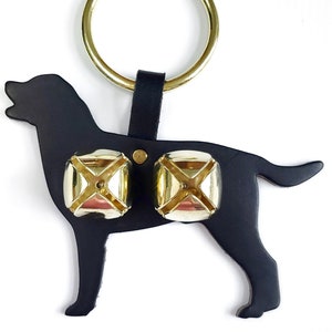 May include: Black leather dog silhouette door knocker with two gold bells. The knocker has a brass ring for hanging.
