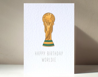 May include: A white card with a gold and green World Cup trophy illustration and the text "Happy Birthday Worlddie".
