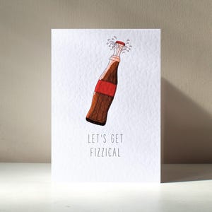 Könnte beinhalten: Eine weiße Karte mit einer Illustration einer braunen und roten Sodaflasche mit rotem Verschluss und sprudelnden Blasen. Der Text "Let's Get Fizzical" ist unter der Flasche gedruckt.
