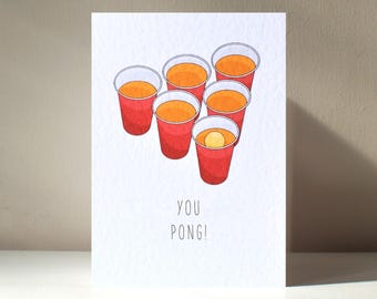 Op de afbeelding: Een witte kaart met een rode en oranje illustratie van een bierpongspel. De tekst "YOU PONG!" staat onder de illustratie.