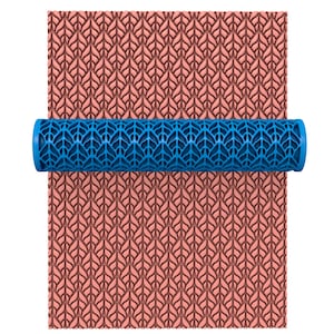 Pode incluir: Um rolo de pastelaria azul com um padrão geométrico. O rolo está a rolar sobre uma superfície rosa com o mesmo padrão em relevo.