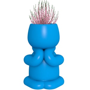 May include: A blue ceramic planter shaped like a person with arms crossed and a small plant with pink flowers growing out of the top.