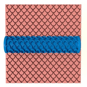 May include: Blue rolling pin with a fish scale pattern, used for creating decorative patterns on fondant or dough.