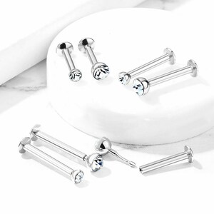 May include: A set of six silver lip rings with clear crystal gems. The rings are available in two sizes, with a straight bar or a curved bar.