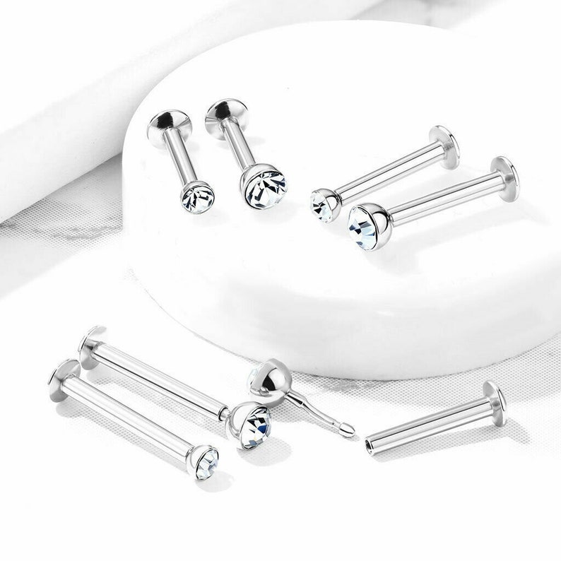 May include: A set of six silver lip rings with clear crystal gems. The rings are available in two sizes, with a straight bar or a curved bar.