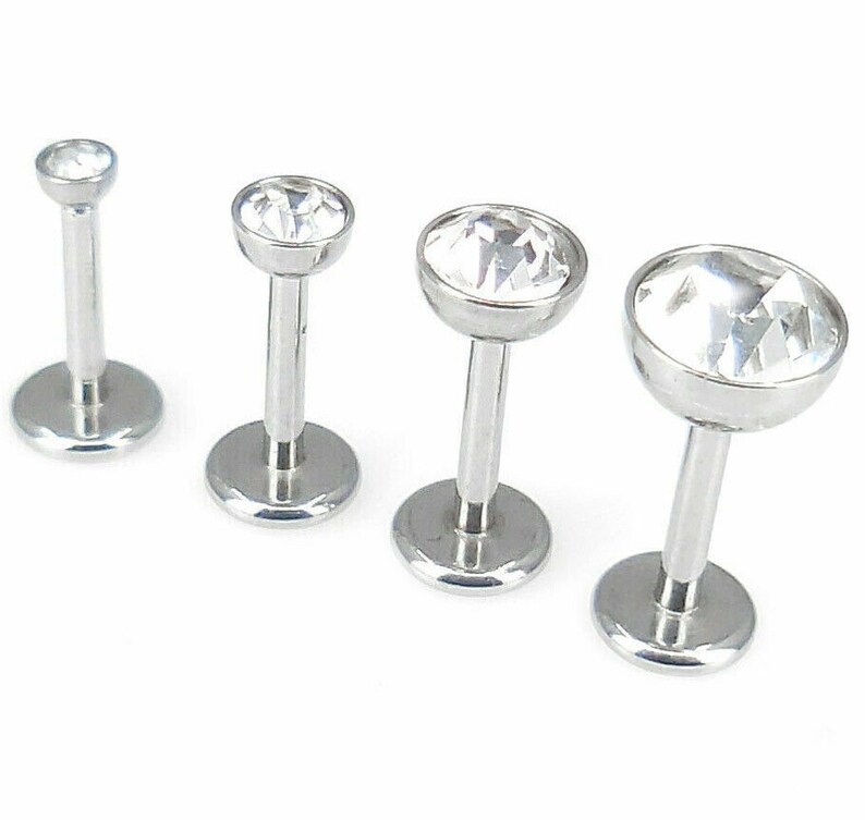 May include: Three silver body jewelry pieces with clear crystal tops. The jewelry is in different sizes.