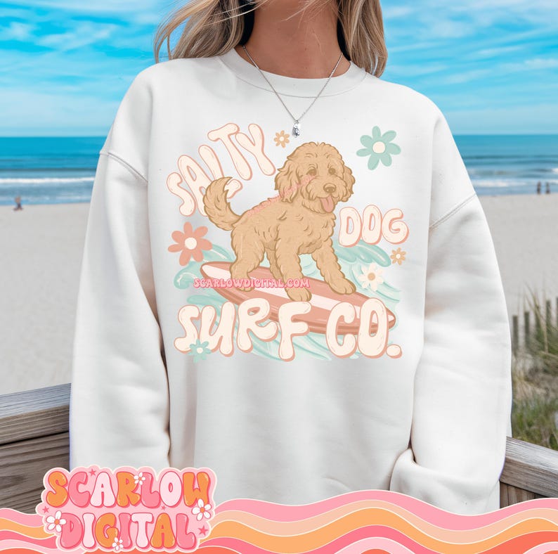 May include: White sweatshirt with a graphic of a dog surfing on a surfboard. The graphic includes the text "Salty Dog Surf Co."