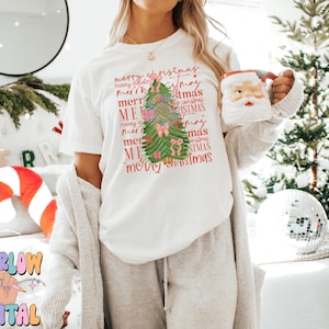 May include: White t-shirt with a green Christmas tree design and the text "merry christmas" repeated in various sizes and colors.