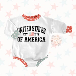 May include: White baby onesie with red and blue trim. The onesie has a graphic print of the American flag and the text "United States Est. 1776 Of America".
