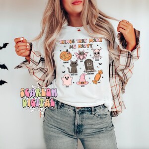Puede incluir: Camiseta blanca con un estampado gr&aacute;fico de art&iacute;culos de tem&aacute;tica de Halloween. El texto en la camiseta dice "Things that make me happy". El gr&aacute;fico incluye calabazas, murci&eacute;lagos, una calavera, un gato negro, un fantasma, un sombrero de bruja, una l&aacute;pida y caramelos.