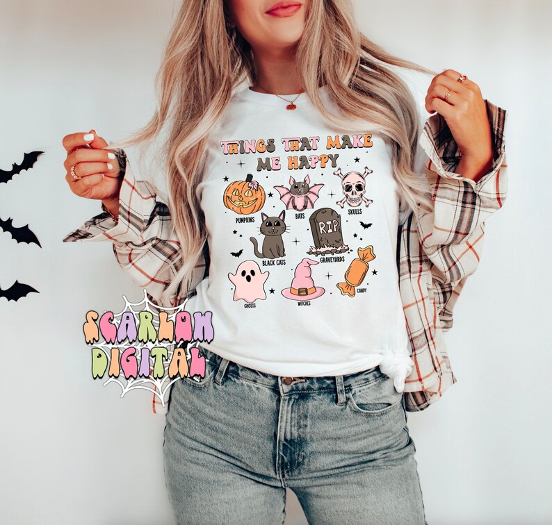 Puede incluir: Camiseta blanca con un estampado gr&aacute;fico de art&iacute;culos de tem&aacute;tica de Halloween. El texto en la camiseta dice "Things that make me happy". El gr&aacute;fico incluye calabazas, murci&eacute;lagos, una calavera, un gato negro, un fantasma, un sombrero de bruja, una l&aacute;pida y caramelos.