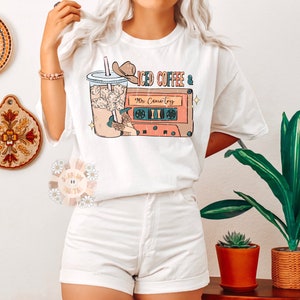 May include: White t-shirt with a graphic of a glass of iced coffee and a cassette tape with the text "Iced Coffee & 90s Country".