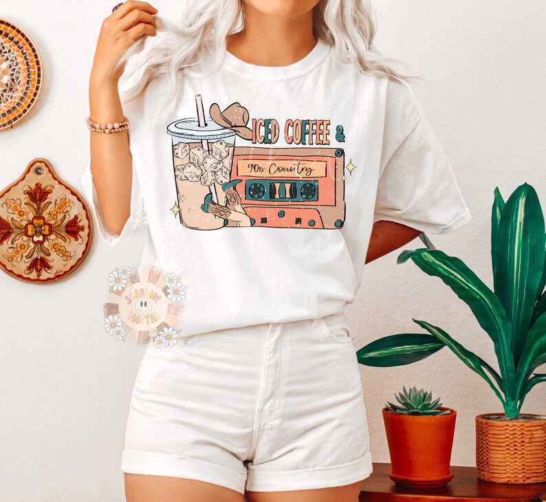 May include: White t-shirt with a graphic of a glass of iced coffee and a cassette tape with the text "Iced Coffee & 90s Country".