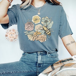 May include: A blue t-shirt with a graphic of a bee and flowers with the text "Sweet Like Honey".