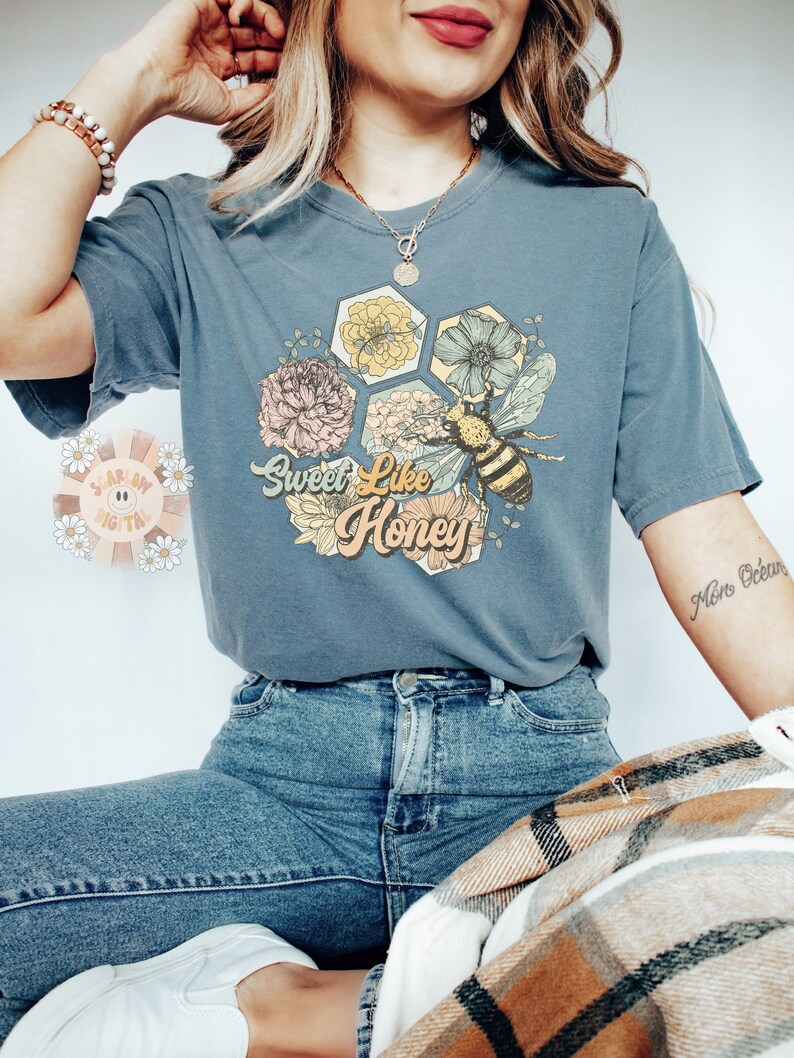 May include: A blue t-shirt with a graphic of a bee and flowers with the text "Sweet Like Honey".