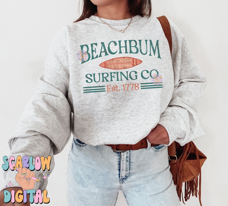 May include: A gray sweatshirt with the text "Beachbum Surfing Co. Est. 1778" in green and orange lettering. The sweatshirt has a graphic of a surfboard with a floral design.