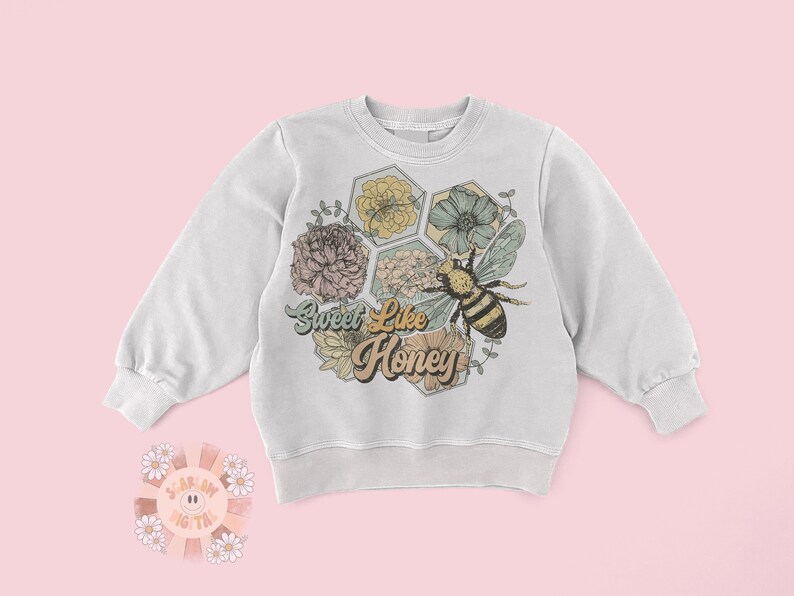 May include: A white sweatshirt with a graphic design of a bee and flowers in a honeycomb pattern. The text "Sweet Like Honey" is printed in a retro font.