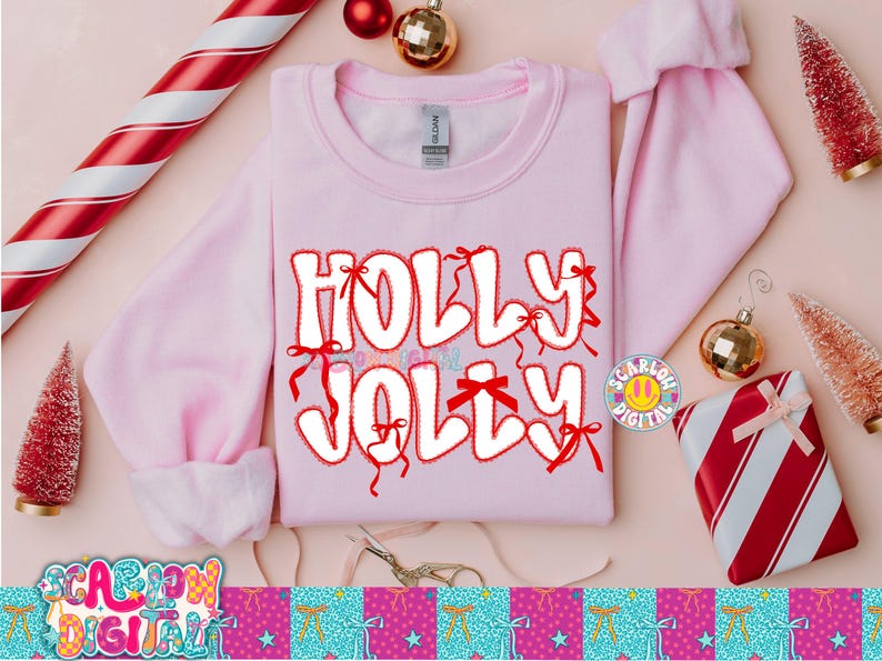 以下が含まれることがあります： 「HOLLY JOLLY」の文字が赤の縁取りとリボンで装飾された白いバブルレターで描かれた、明るいピンク色のスウェットシャツ。オーナメントや包装されたギフトなど、クリスマスをテーマにした装飾がスウェットシャツを囲んでいます。