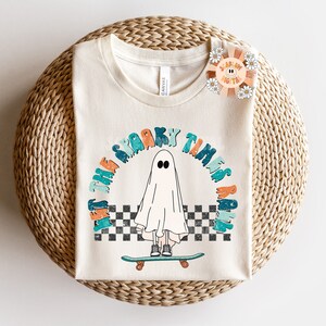 May include: A white t-shirt with a graphic of a ghost skateboarding and the text "Let the spooky times roll".