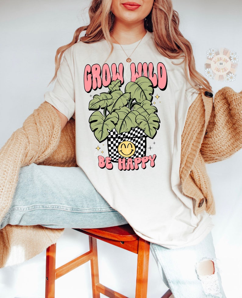 May include: A white t-shirt with a pink and green graphic that says "Grow Wild Be Happy". The graphic features a potted plant with a smiley face.