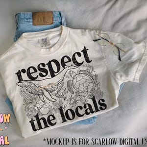 K&ouml;nnte beinhalten: Ein wei&szlig;es T-Shirt mit einem schwarzen Grafikdesign aus einem Wal, einer Meeresschildkr&ouml;te und einem Korallenriff. Der Text "respect the locals" ist in Schwarz auf das Shirt gedruckt.