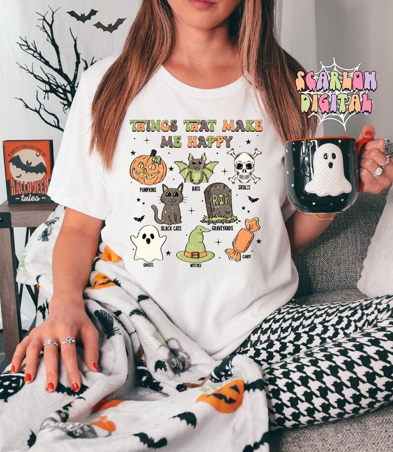 May include: White t-shirt with the text "Things that make me happy" and illustrations of pumpkins, bats, skulls, black cats, graveyards, ghosts, witches, and candy.