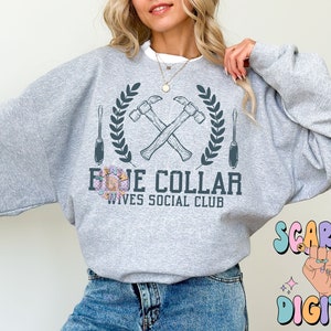 May include: Gray sweatshirt with a graphic of crossed hammers and screwdrivers with a laurel wreath around them. The text "Blue Collar Wives Social Club" is below the graphic.