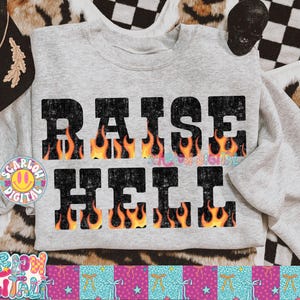 Può includere: Felpa grigio chiaro con la scritta "RAISE HELL" in grandi lettere nere sbiadite. Le lettere presentano un design a fiamma arancione e gialla. Un berretto nero Harley-Davidson è visibile nell'angolo in alto a sinistra.