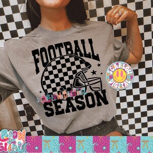 Pode incluir: Uma camiseta cinza com um gr&aacute;fico de capacete de futebol xadrez em preto e branco e as palavras "FOOTBALL SEASON". A camisa tamb&eacute;m tem um logotipo circular colorido com um rosto sorridente e as palavras "SCARLOW DIGITAL".